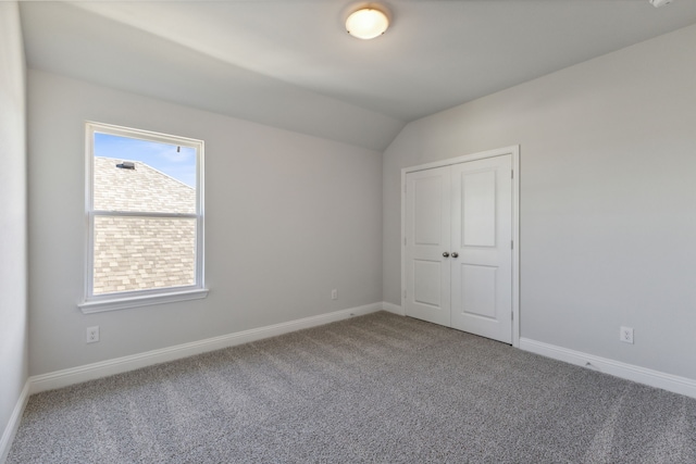 interior space with lofted ceiling, carpet, baseboards, and a closet