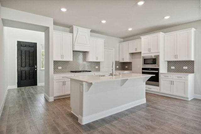 kitchen featuring light wood finished floors, custom exhaust hood, stainless steel appliances, and a sink