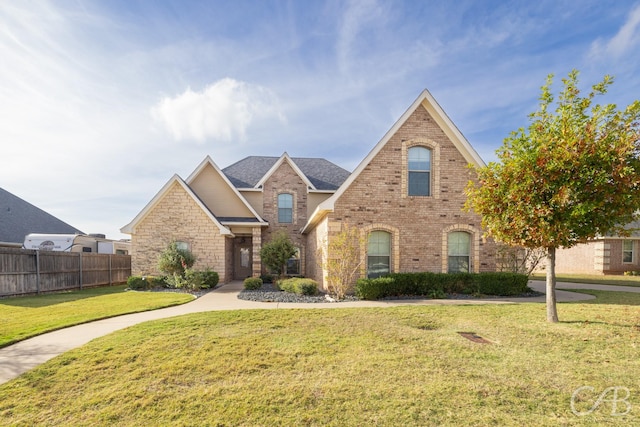 view of front of property featuring a front yard, brick siding, and fence