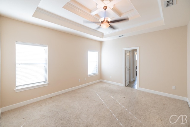 empty room featuring light carpet, visible vents, baseboards, ornamental molding, and a tray ceiling