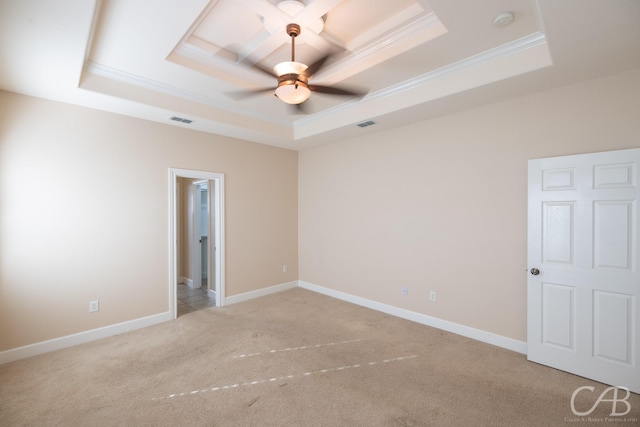 spare room with crown molding, a raised ceiling, visible vents, light carpet, and baseboards