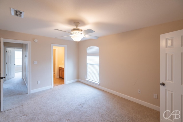 unfurnished bedroom featuring baseboards, ceiling fan, visible vents, and light colored carpet