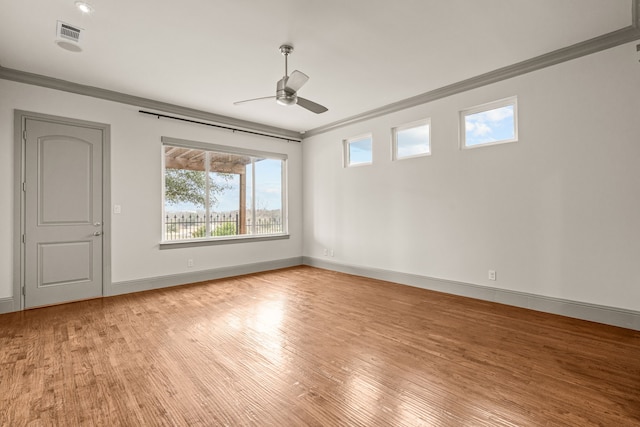 spare room featuring ceiling fan, wood finished floors, visible vents, baseboards, and ornamental molding