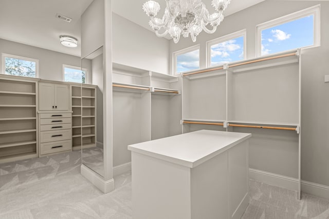 spacious closet with a chandelier, light colored carpet, and visible vents