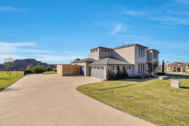 view of front of home with stucco siding, concrete driveway, fence, a residential view, and a front lawn