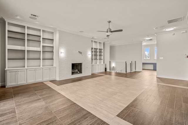 unfurnished living room with a ceiling fan, visible vents, built in features, ornamental molding, and a brick fireplace