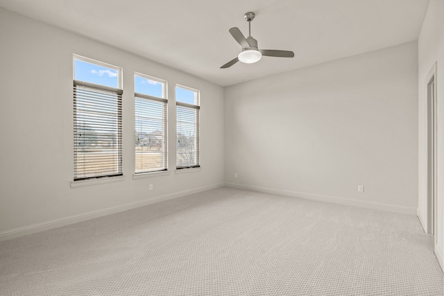 spare room featuring light carpet, ceiling fan, and baseboards