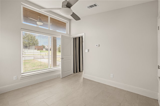 unfurnished room with ceiling fan, visible vents, and baseboards