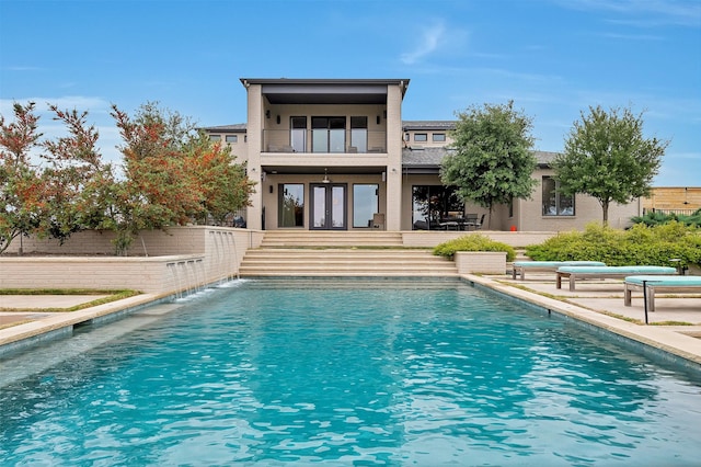 rear view of house with a patio, french doors, a balcony, and an outdoor pool