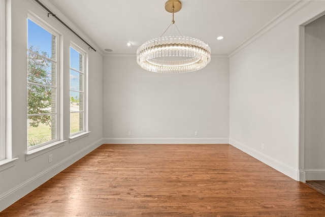 empty room featuring crown molding, recessed lighting, an inviting chandelier, wood finished floors, and baseboards