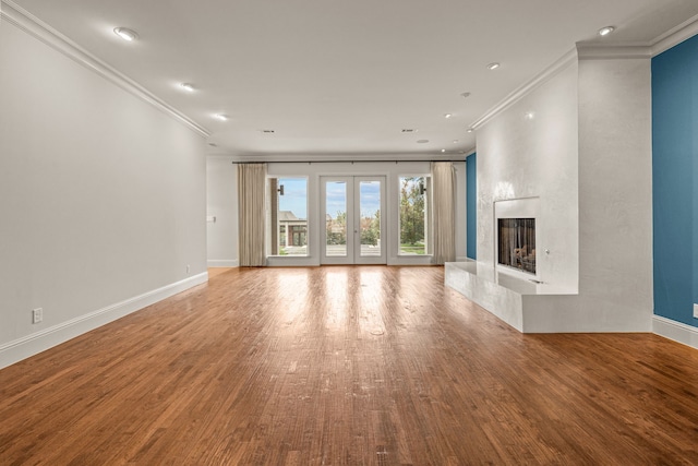 unfurnished living room with crown molding, a fireplace, baseboards, and wood finished floors