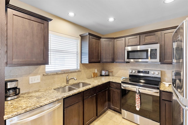 kitchen with light tile patterned floors, dark brown cabinetry, stainless steel appliances, a sink, and backsplash