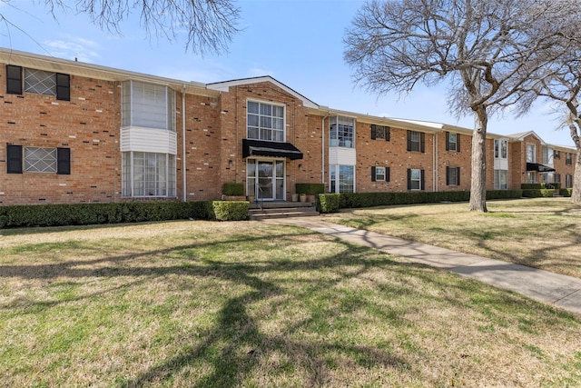 townhome / multi-family property with brick siding and a front yard