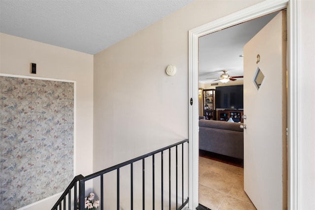 hall with light tile patterned floors and a textured ceiling