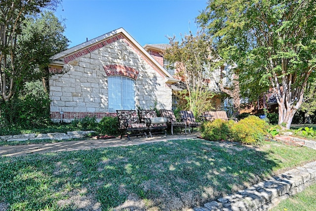 3611 Moroney Dr, Richardson, TX 75082 - view of side of home featuring a yard, stone siding, and a patio