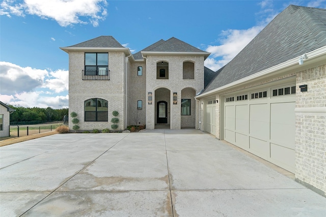 view of front of home with an attached garage, roof with shingles, concrete driveway, and brick siding