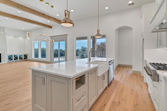 kitchen with arched walkways, light wood-type flooring, a sink, and custom exhaust hood