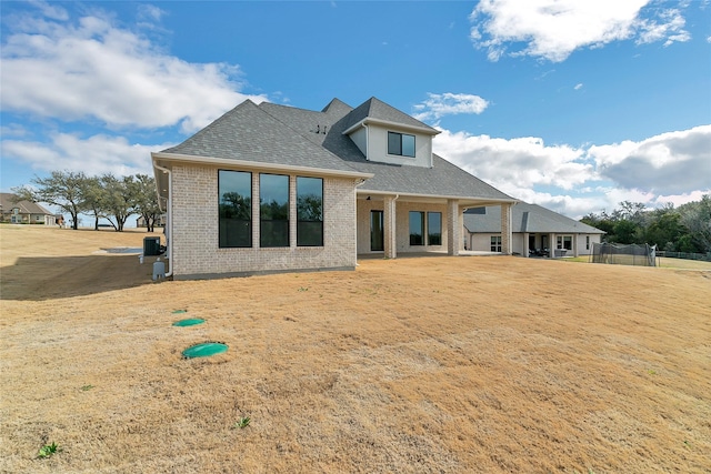 rear view of property with roof with shingles and brick siding