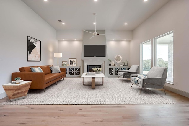 living area featuring recessed lighting, a fireplace, baseboards, and wood finished floors