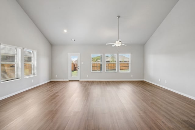 unfurnished living room with ceiling fan, high vaulted ceiling, wood finished floors, visible vents, and baseboards