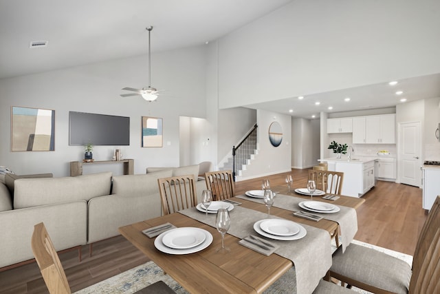 dining area with light wood finished floors, visible vents, a ceiling fan, stairway, and recessed lighting