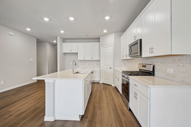 kitchen with a center island with sink, stainless steel appliances, tasteful backsplash, a sink, and wood finished floors