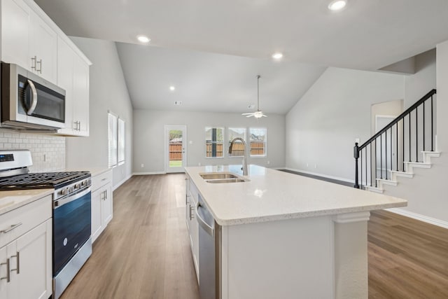 kitchen featuring vaulted ceiling, appliances with stainless steel finishes, light wood-type flooring, and a sink