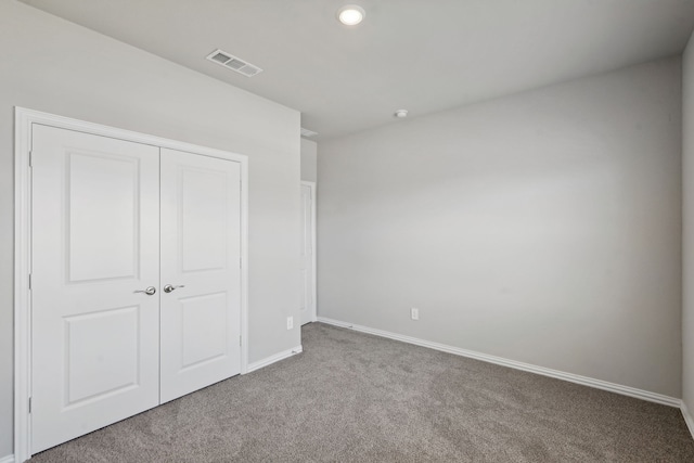 unfurnished bedroom with carpet, a closet, visible vents, and baseboards