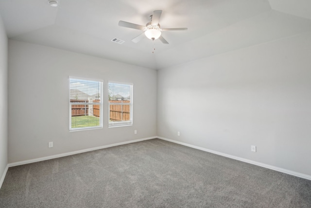 carpeted empty room with lofted ceiling, baseboards, visible vents, and a ceiling fan