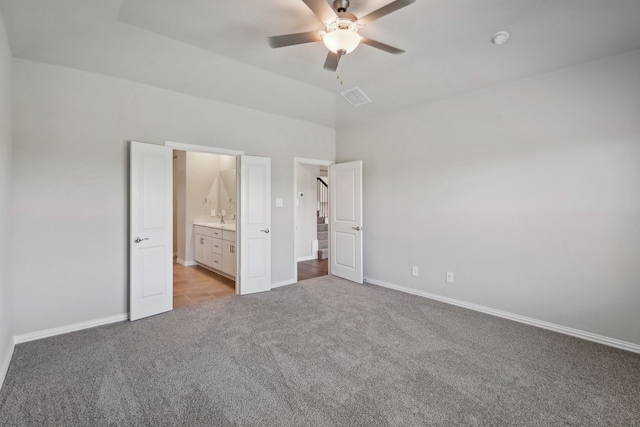 unfurnished bedroom featuring light colored carpet, visible vents, a ceiling fan, vaulted ceiling, and baseboards