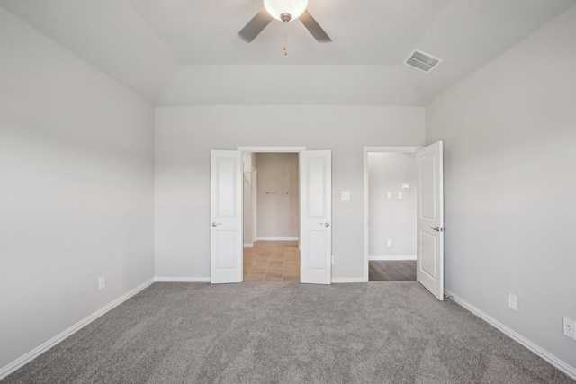 unfurnished bedroom featuring baseboards, visible vents, lofted ceiling, ceiling fan, and carpet flooring