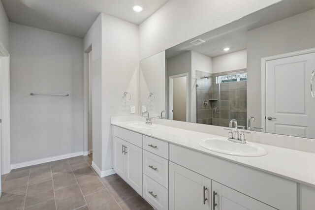 bathroom featuring a stall shower, a sink, baseboards, and double vanity