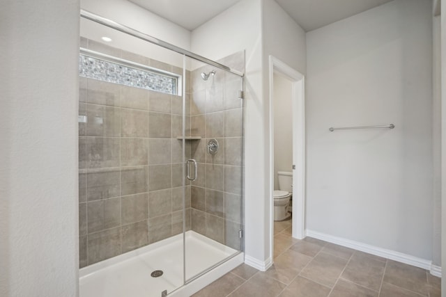 full bath featuring a stall shower, tile patterned floors, toilet, and baseboards