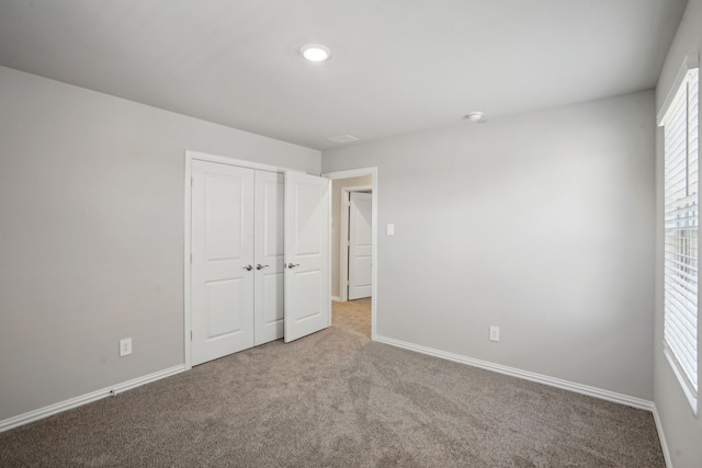 unfurnished bedroom featuring carpet floors, a closet, and baseboards