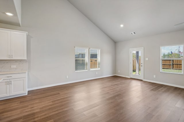 unfurnished living room with wood finished floors, visible vents, and baseboards