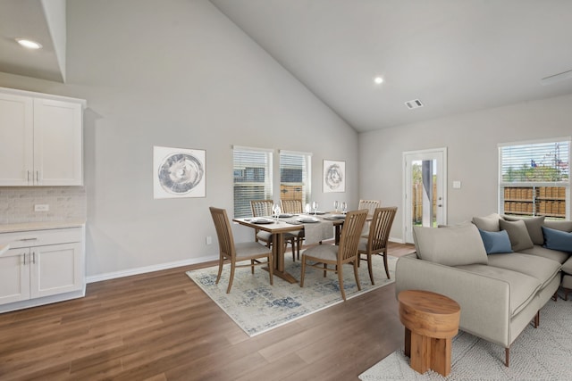 dining area with baseboards, visible vents, wood finished floors, high vaulted ceiling, and recessed lighting