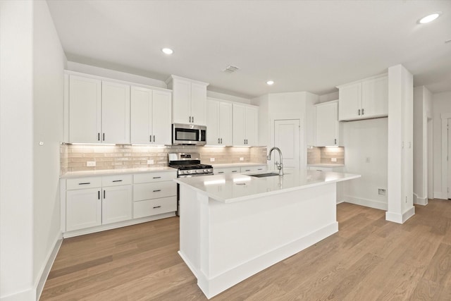 kitchen featuring a sink, visible vents, white cabinets, appliances with stainless steel finishes, and light wood finished floors