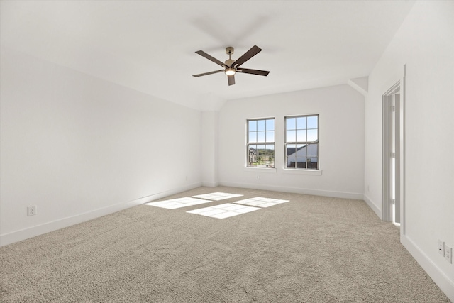 spare room with a ceiling fan, carpet, vaulted ceiling, and baseboards