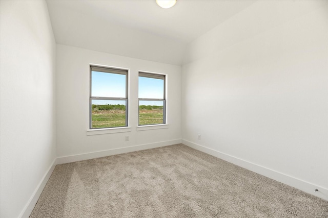 spare room featuring lofted ceiling, light carpet, and baseboards