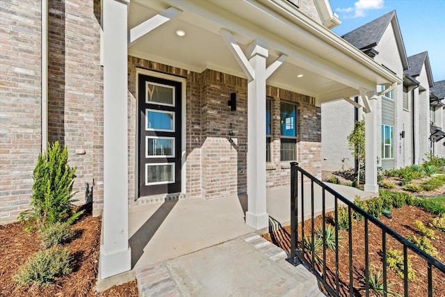 doorway to property featuring covered porch and brick siding