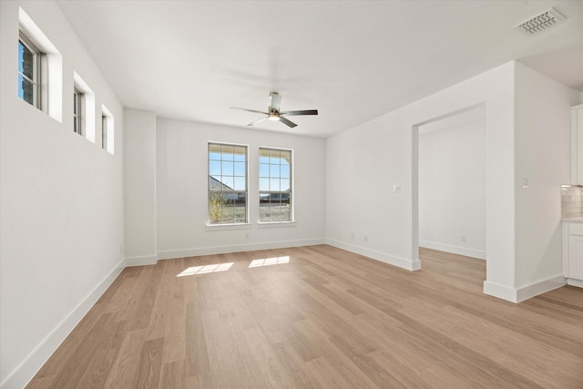 empty room with light wood-style floors, visible vents, baseboards, and a ceiling fan