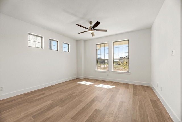 spare room featuring light wood finished floors, baseboards, and a ceiling fan