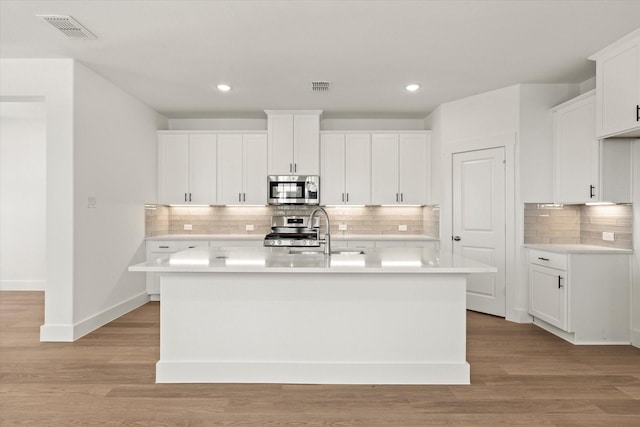 kitchen featuring stainless steel appliances, light wood-type flooring, visible vents, and a sink