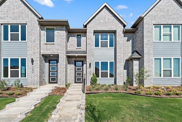 view of property with a front yard and brick siding