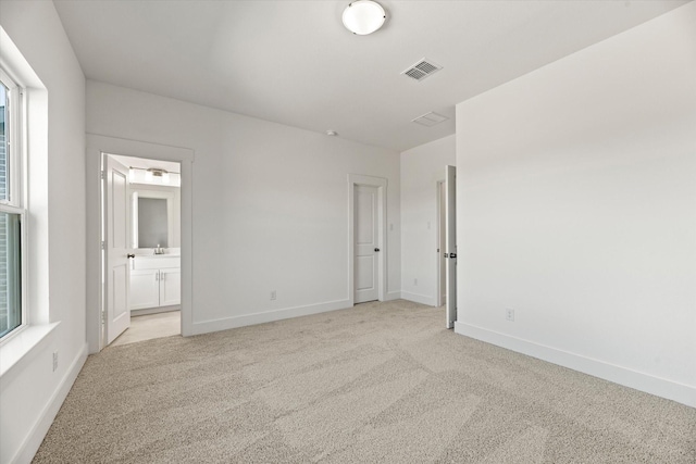 unfurnished bedroom featuring light carpet, visible vents, and baseboards