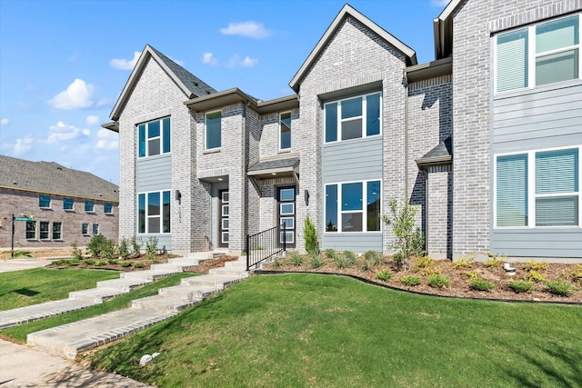 townhome / multi-family property featuring brick siding and a front lawn