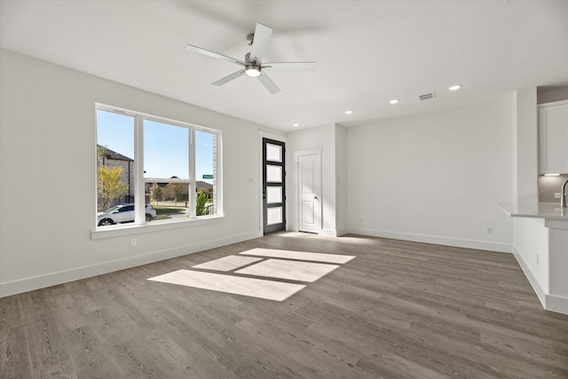 unfurnished living room featuring baseboards, visible vents, wood finished floors, and recessed lighting