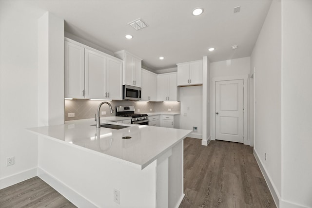 kitchen with visible vents, decorative backsplash, appliances with stainless steel finishes, a sink, and a peninsula