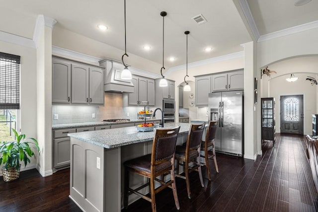 kitchen with appliances with stainless steel finishes, arched walkways, gray cabinets, and visible vents