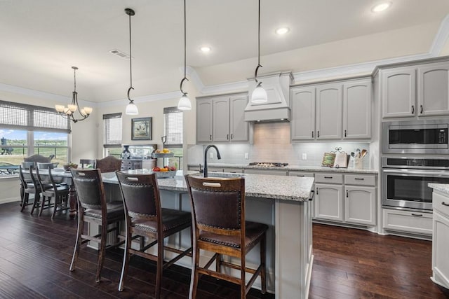 kitchen with a sink, appliances with stainless steel finishes, custom exhaust hood, backsplash, and dark wood-style floors